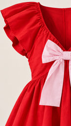 Close-up detail of red fabric, flutter shoulder ruffle, and pink front bow