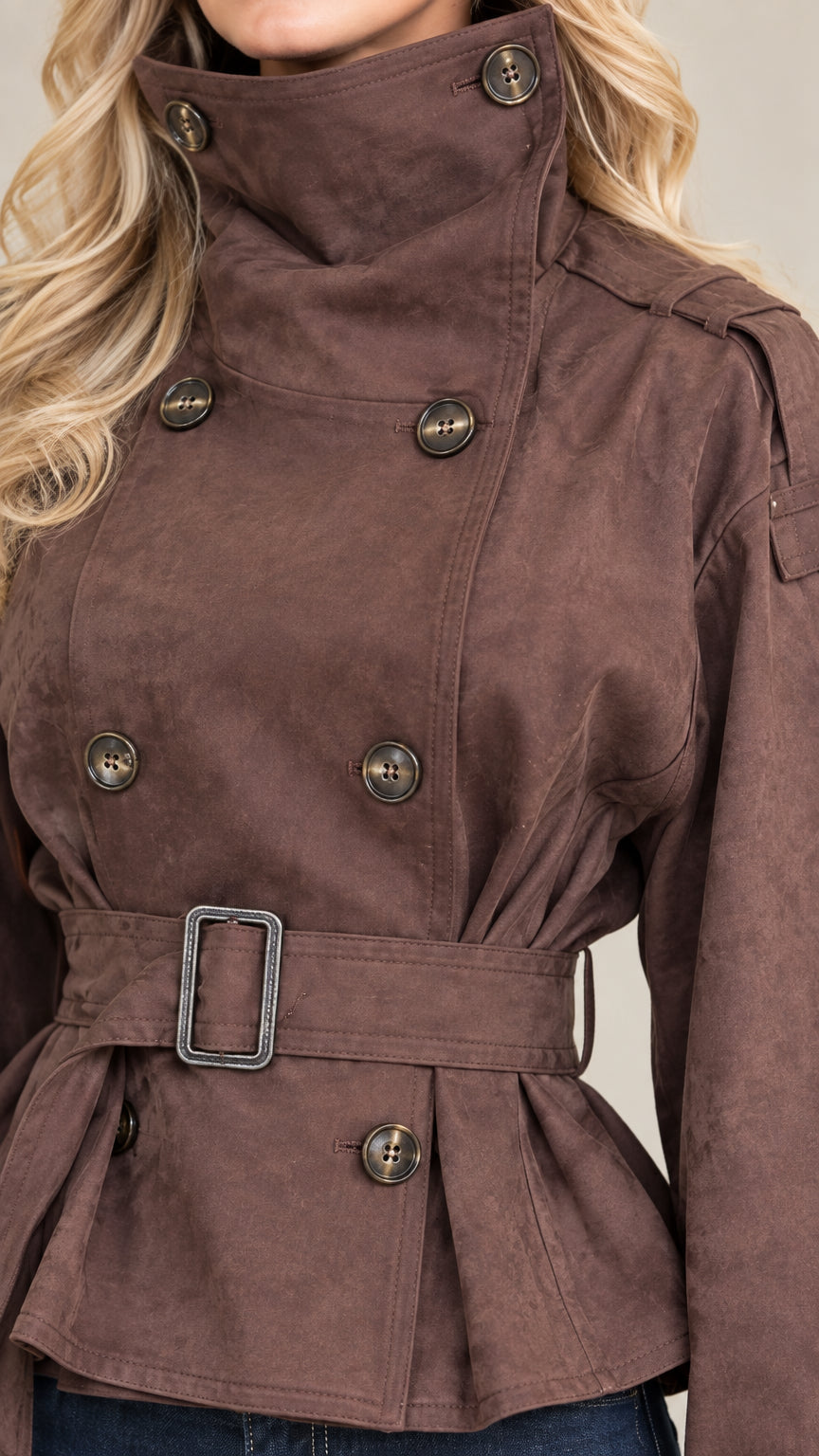 Close-up detail of brown cropped jacket collar, epaulets, buttons, and belt buckle