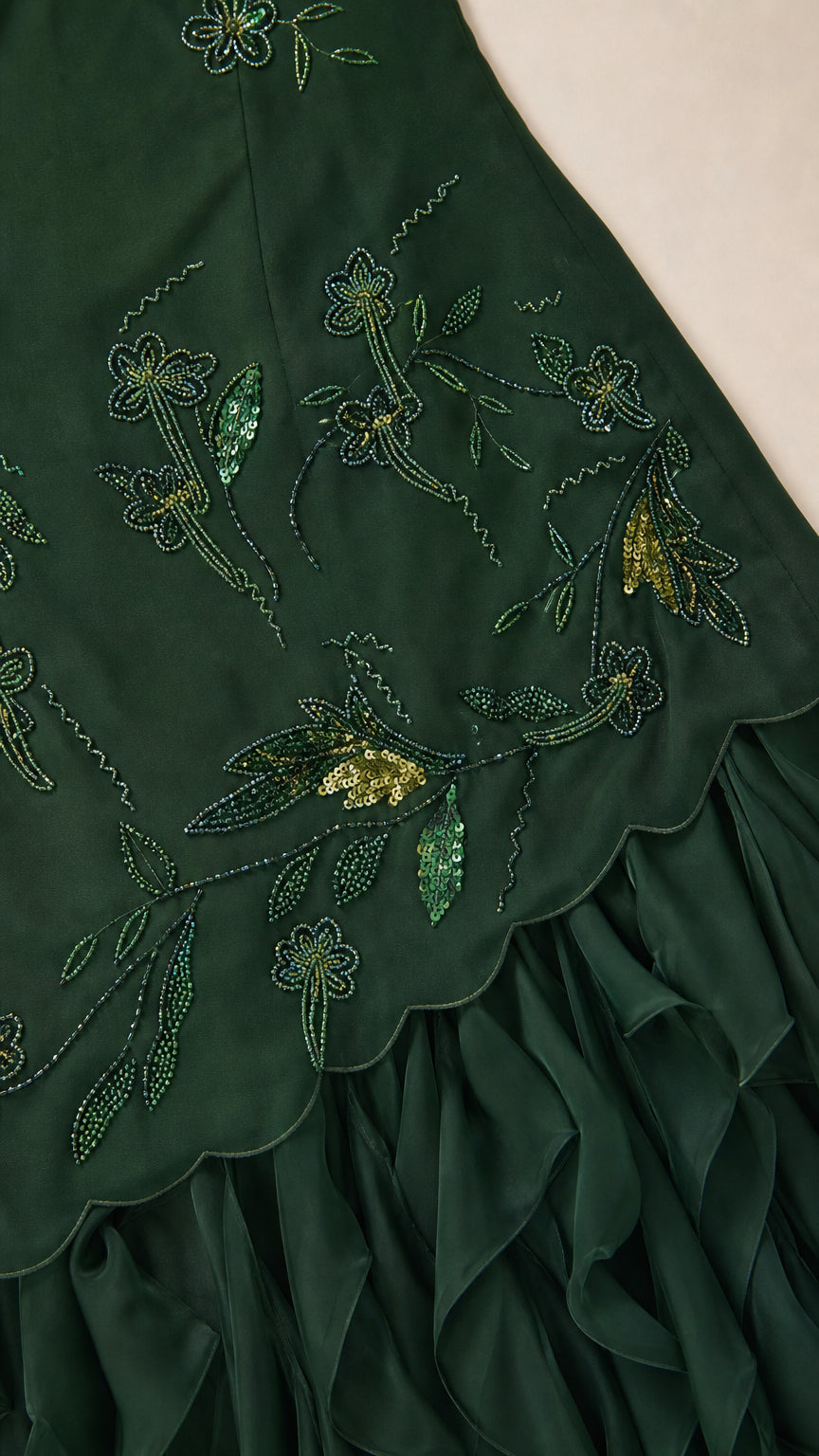 Close-up detail of embroidered floral beadwork and scalloped ruffle hem