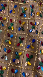 Close-up detail of sequin grid fabric with colorful crystal floral embellishments
