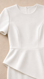 Close-up detail of white crew neckline, bodice tailoring, and asymmetrical peplum waist