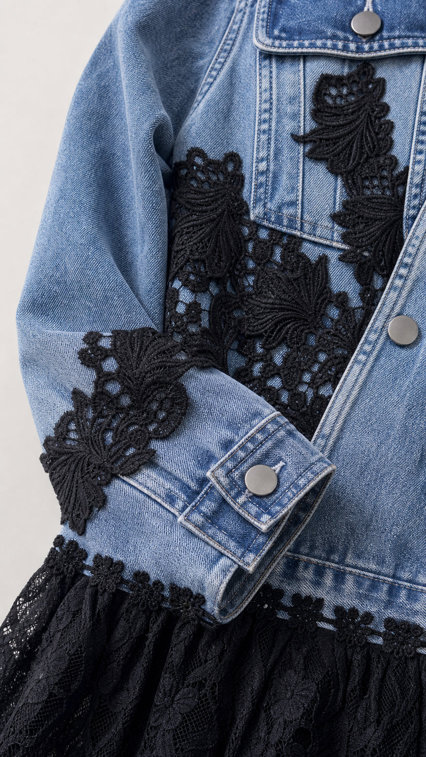 Close-up detail of light blue denim sleeve cuff and jacket with black floral embroidery