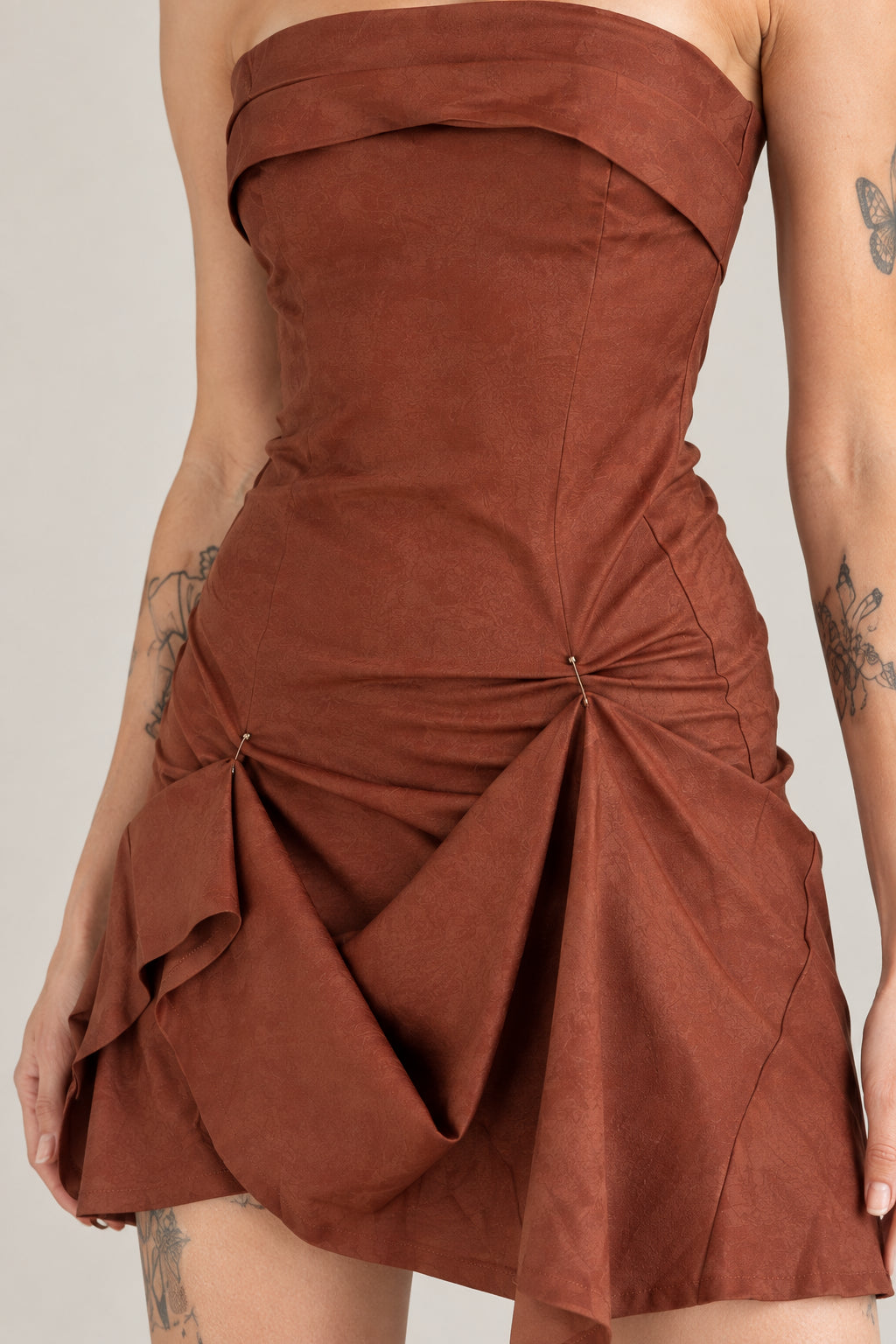 Close-up detail of rust brown fabric texture and gathered drape on skirt