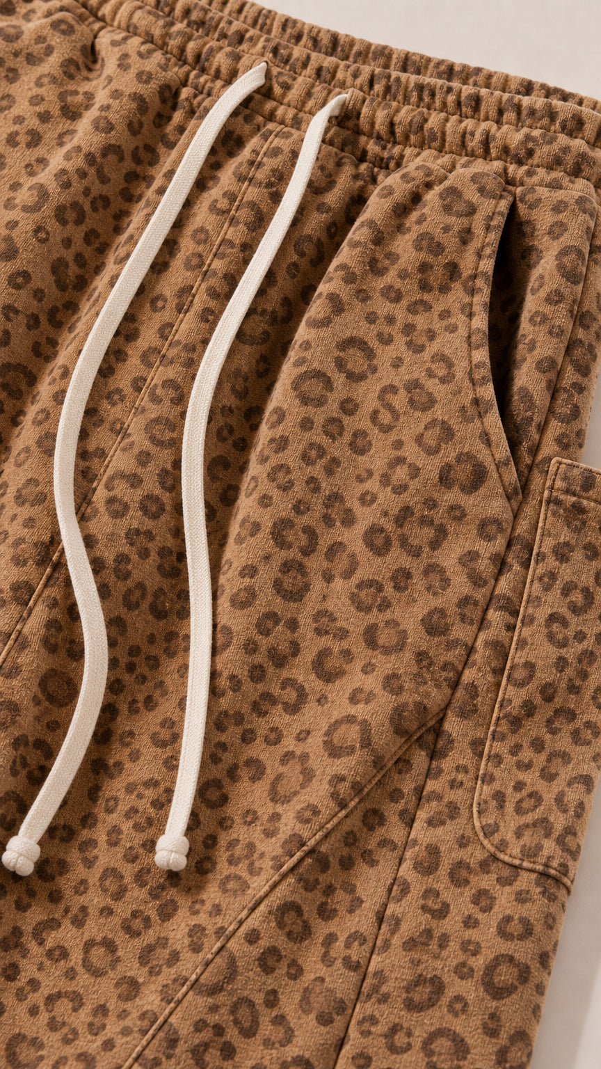 Close-up detail of elastic waistband, drawstring, pocket, and leopard print texture