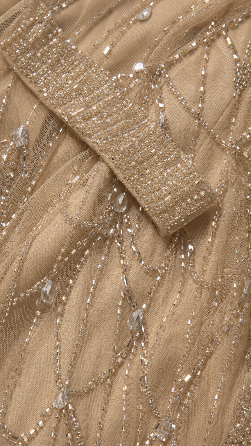 Close-up detail of champagne mesh fabric with intricate beadwork and crystal accents
