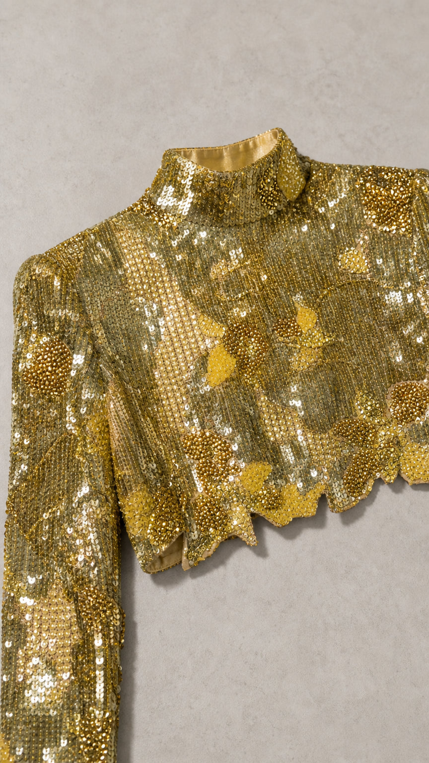 Close-up detail of gold sequin fabric pattern and scalloped hemline