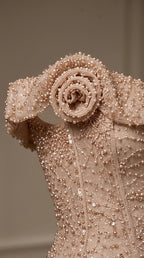 Close-up detail of blush pink beaded fabric and floral rosette shoulder accent