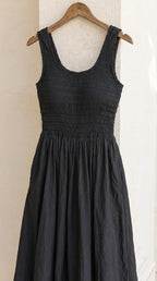 Detailed view of black smocked bodice dress on wooden hanger