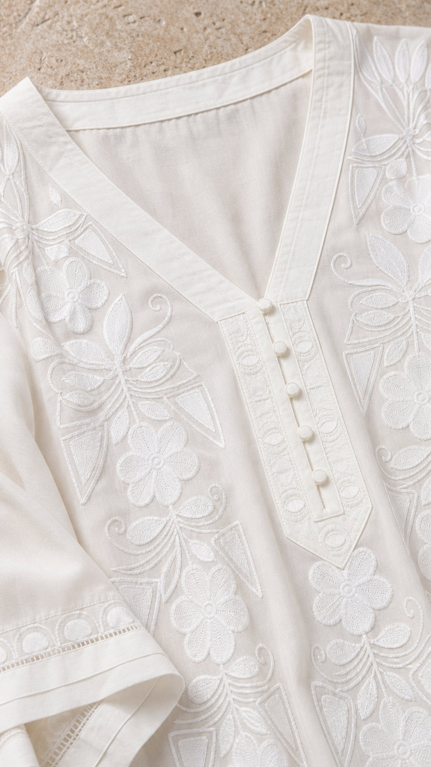 Close-up detail of white kaftan neckline with intricate floral embroidery and button placket