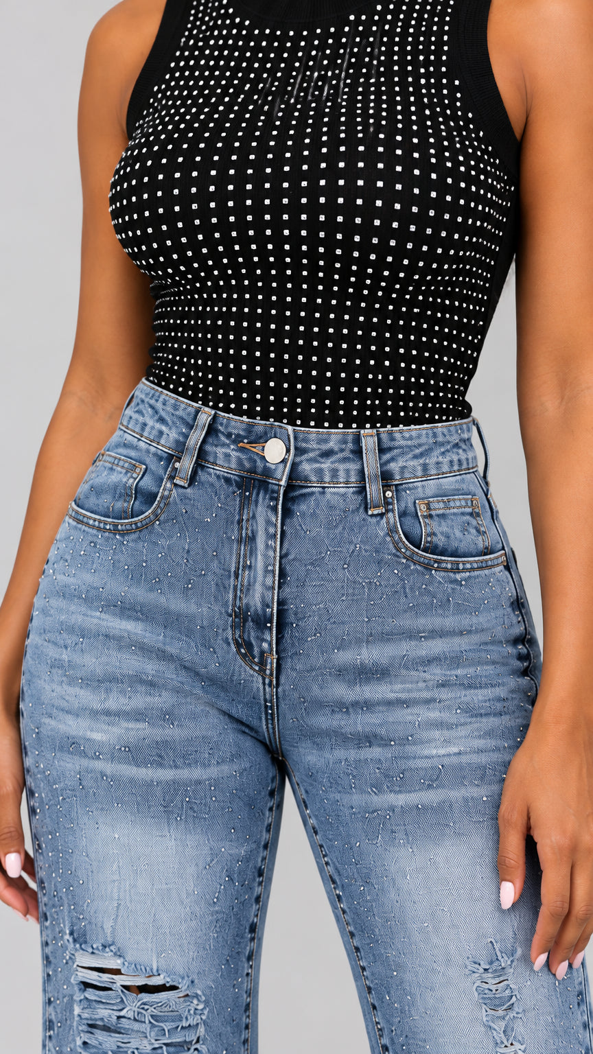 Close-up detail of rhinestone studded black tank top and high-rise waistband on flare jeans