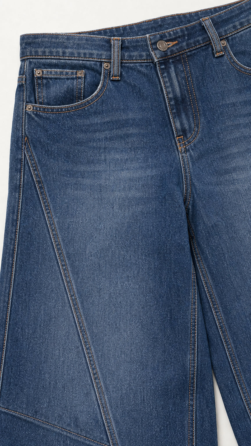 Close-up detail of medium blue jeans waistband, pockets, and diagonal front seam construction