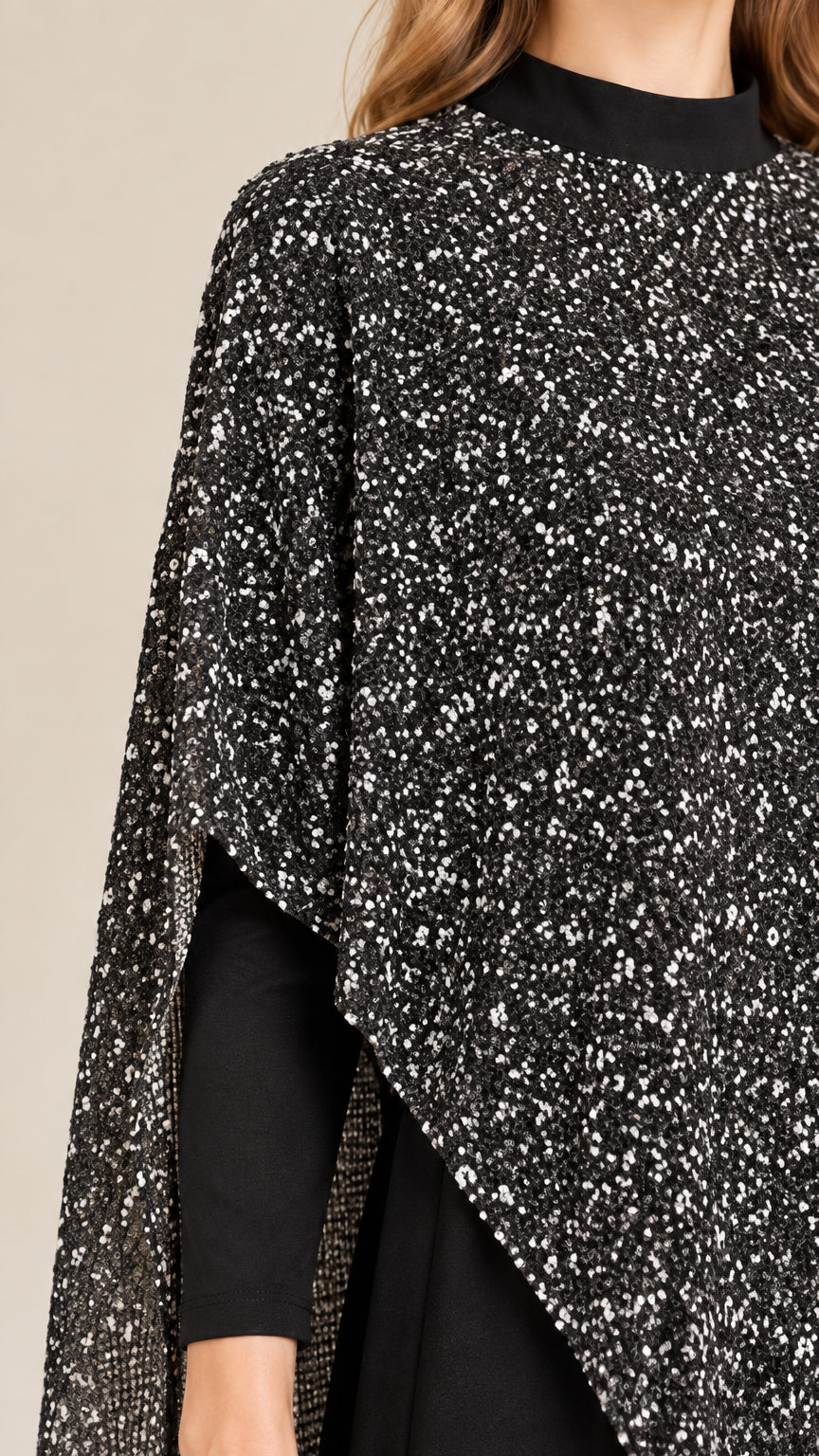 Close-up detail of textured speckled cape fabric, mock neckline, and fitted sleeve