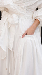 Close-up detail of pocket and tie belt on white maxi dress