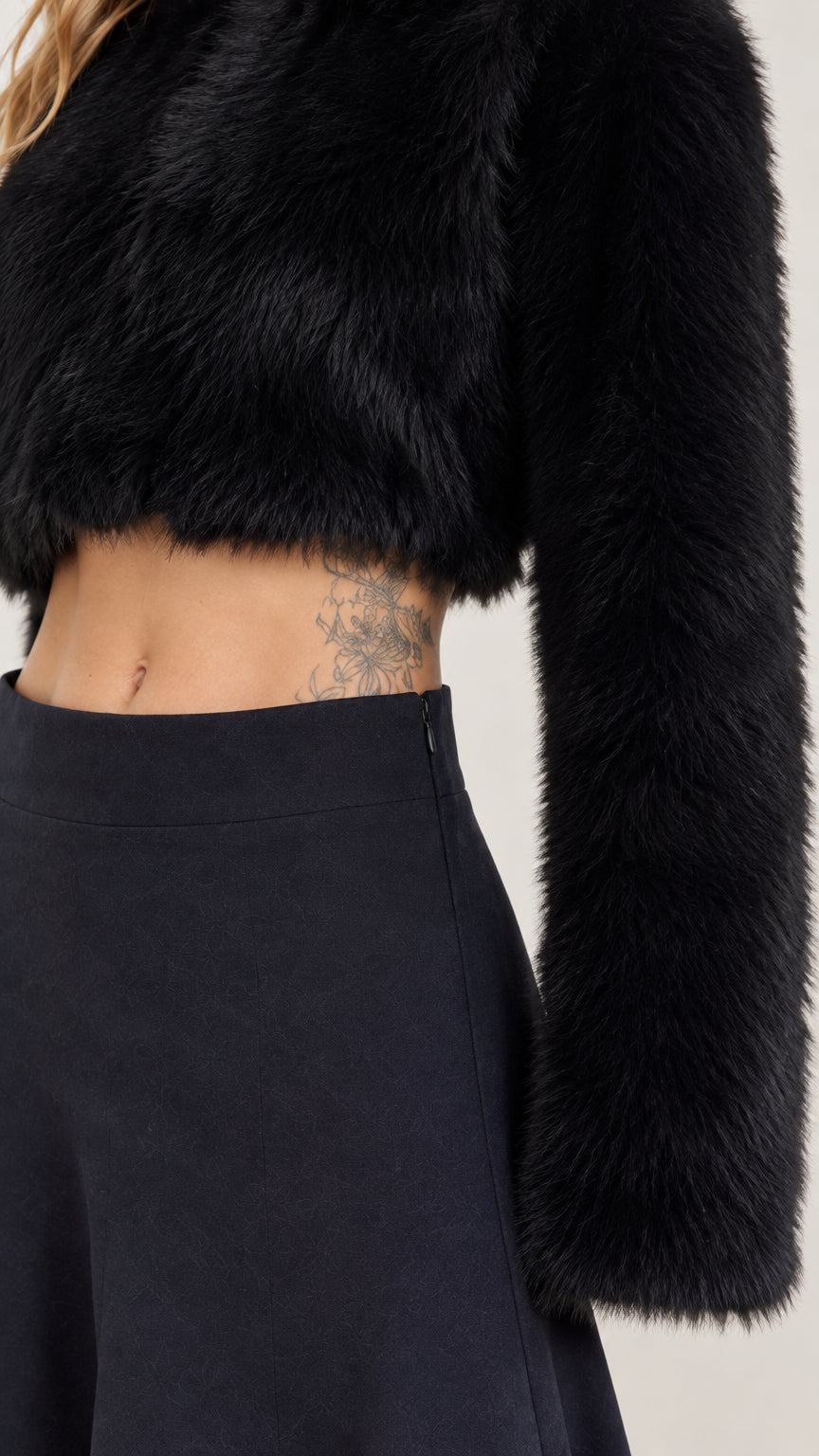 Close-up detail of black fuzzy crop top texture and skirt waistband