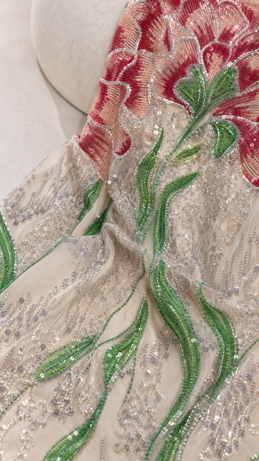 Detailed close-up of intricate red floral and green vine sequin and bead embroidery