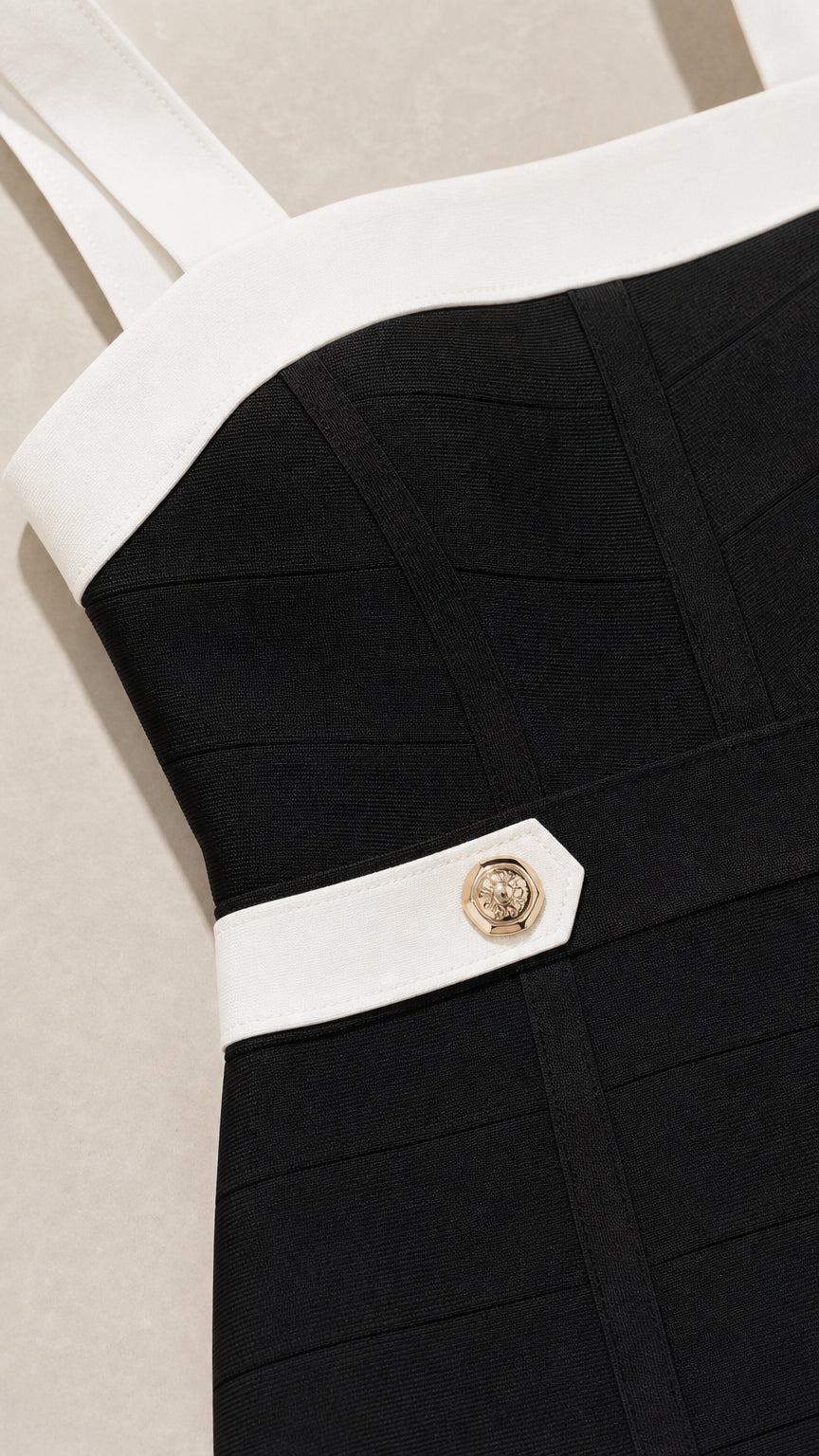 Close-up detail of dense bandage knit fabric, white contrast border, and embossed gold button