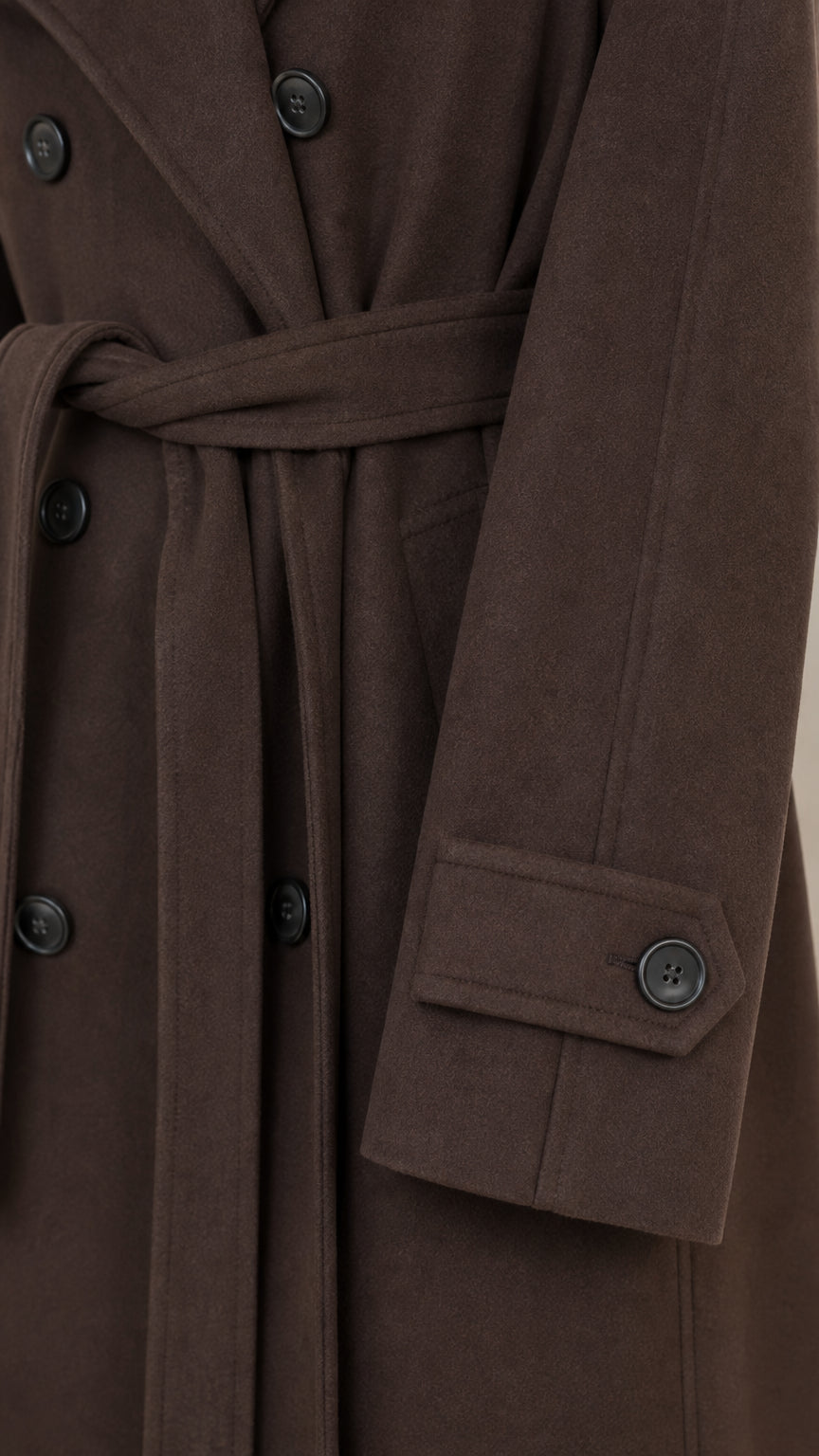 Close-up detail of dark brown coat fabric, buttons, and sleeve cuff tab
