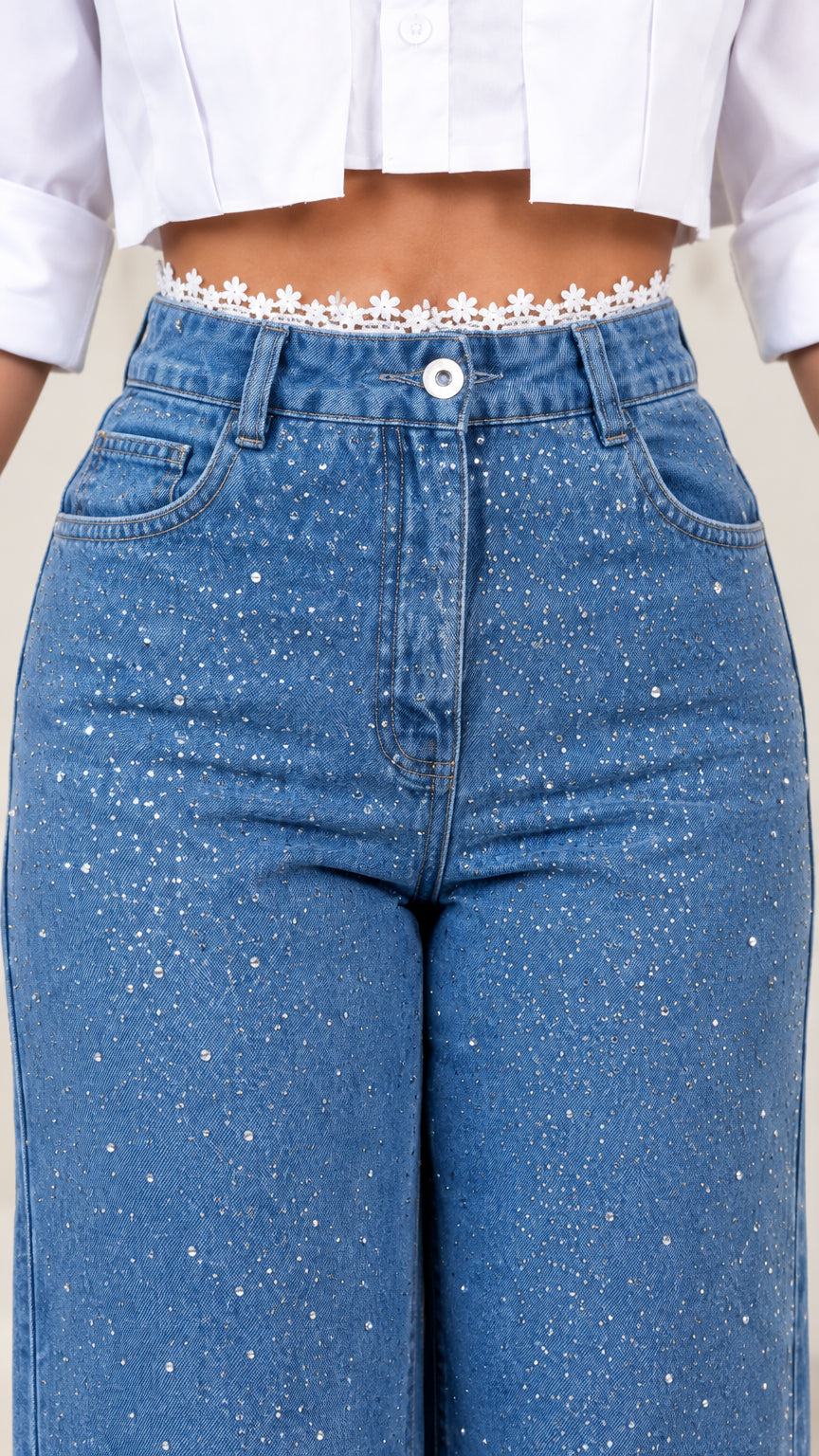 Close-up detail of high waist button fly, rhinestone jeans fabric, and floral lace shirt hem