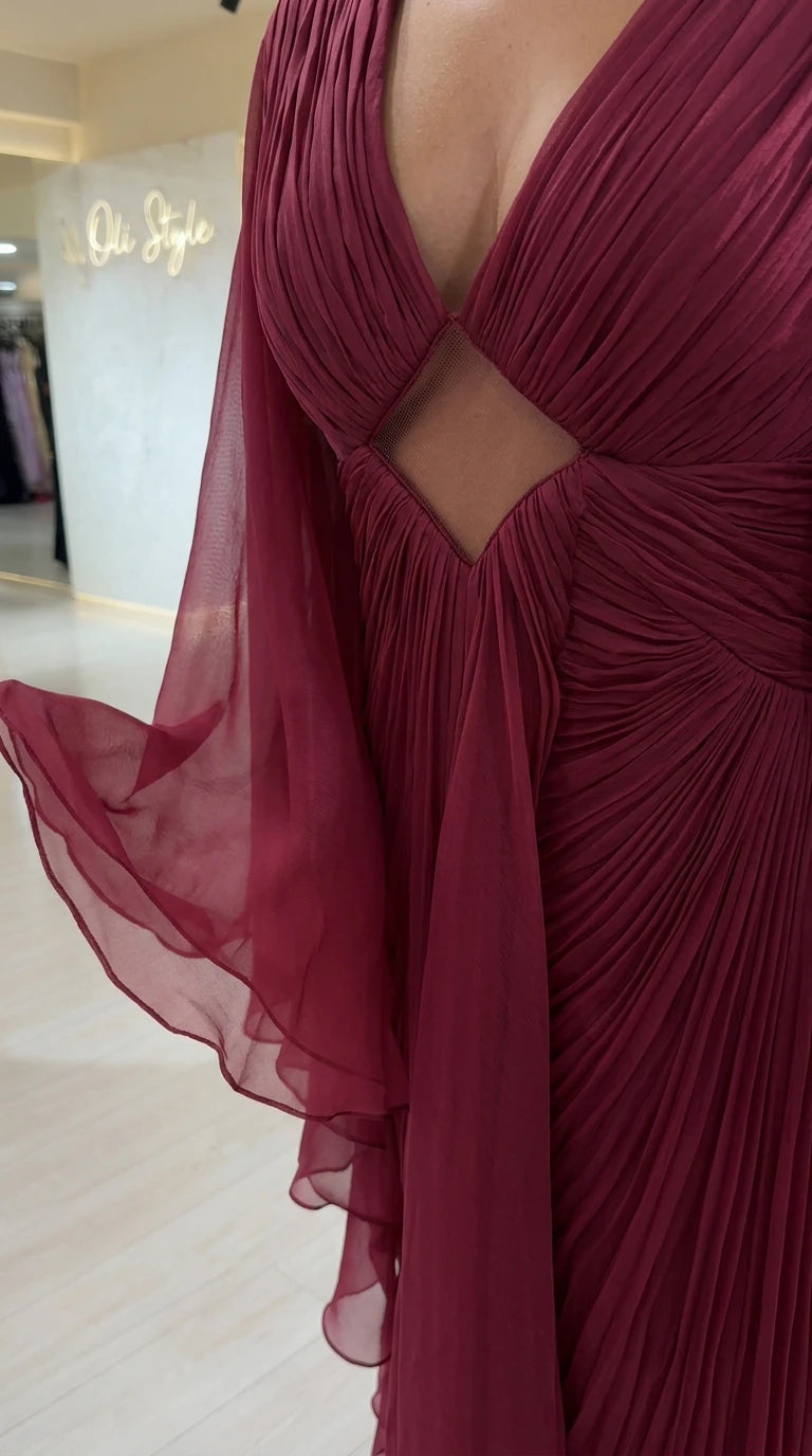 Close-up detail of pleated texture, plunge neckline, and diamond midriff cutout on burgundy gown
