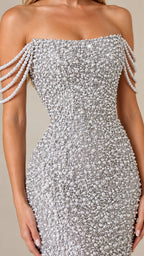 Close-up detail of strapless neckline and tiered draped pearl strands on silver dress