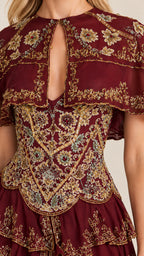 Close-up detail of ornate gold and colorful embroidery and front keyhole on burgundy bodice