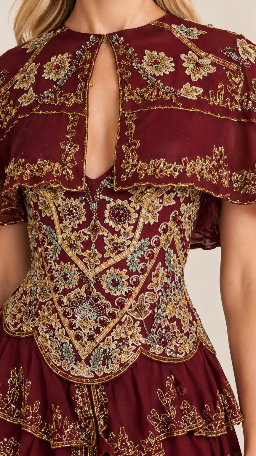 Close-up detail of ornate gold and colorful embroidery and front keyhole on burgundy bodice
