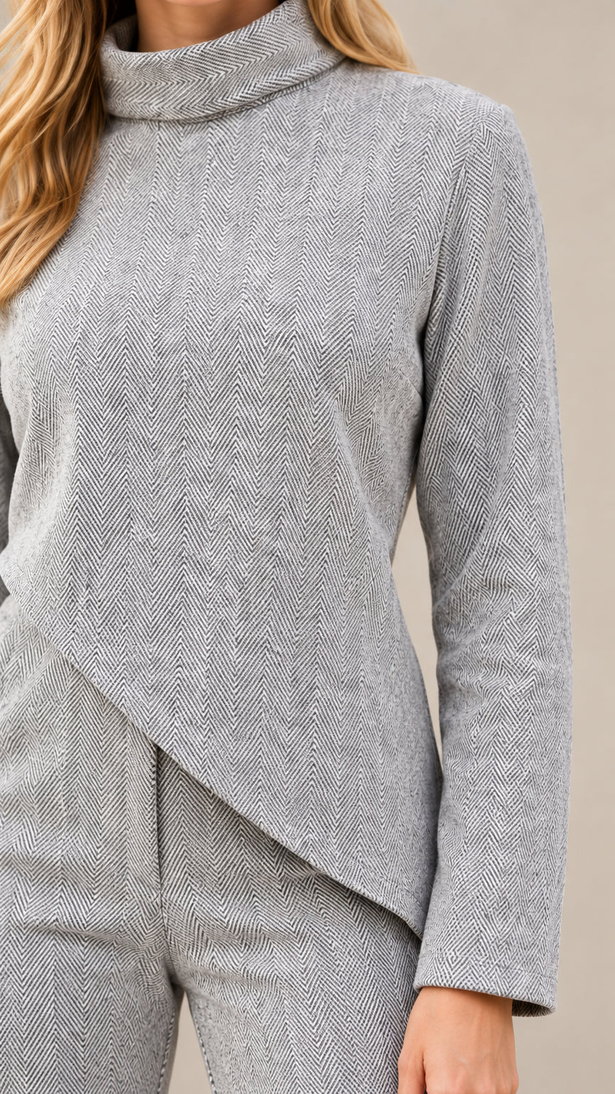 Close-up detail of textured fabric, high funnel neckline, and asymmetric hem