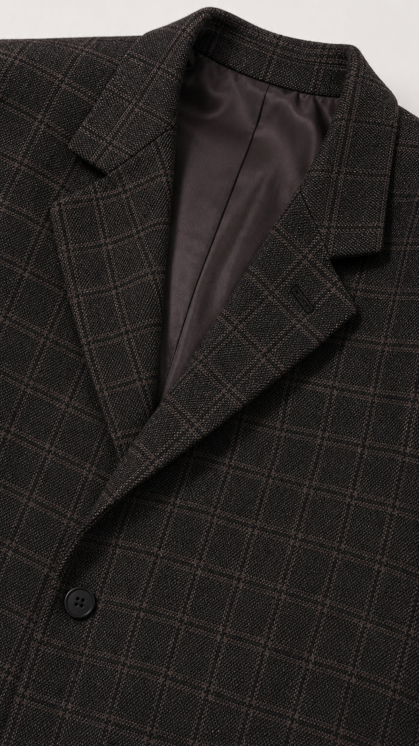 Close-up detail of blazer notch lapel, dark plaid texture, and inner lining
