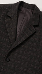 Close-up detail of blazer notch lapel, dark plaid texture, and inner lining