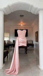 Mannequin display of blush pink strapless mini dress with long side sash train