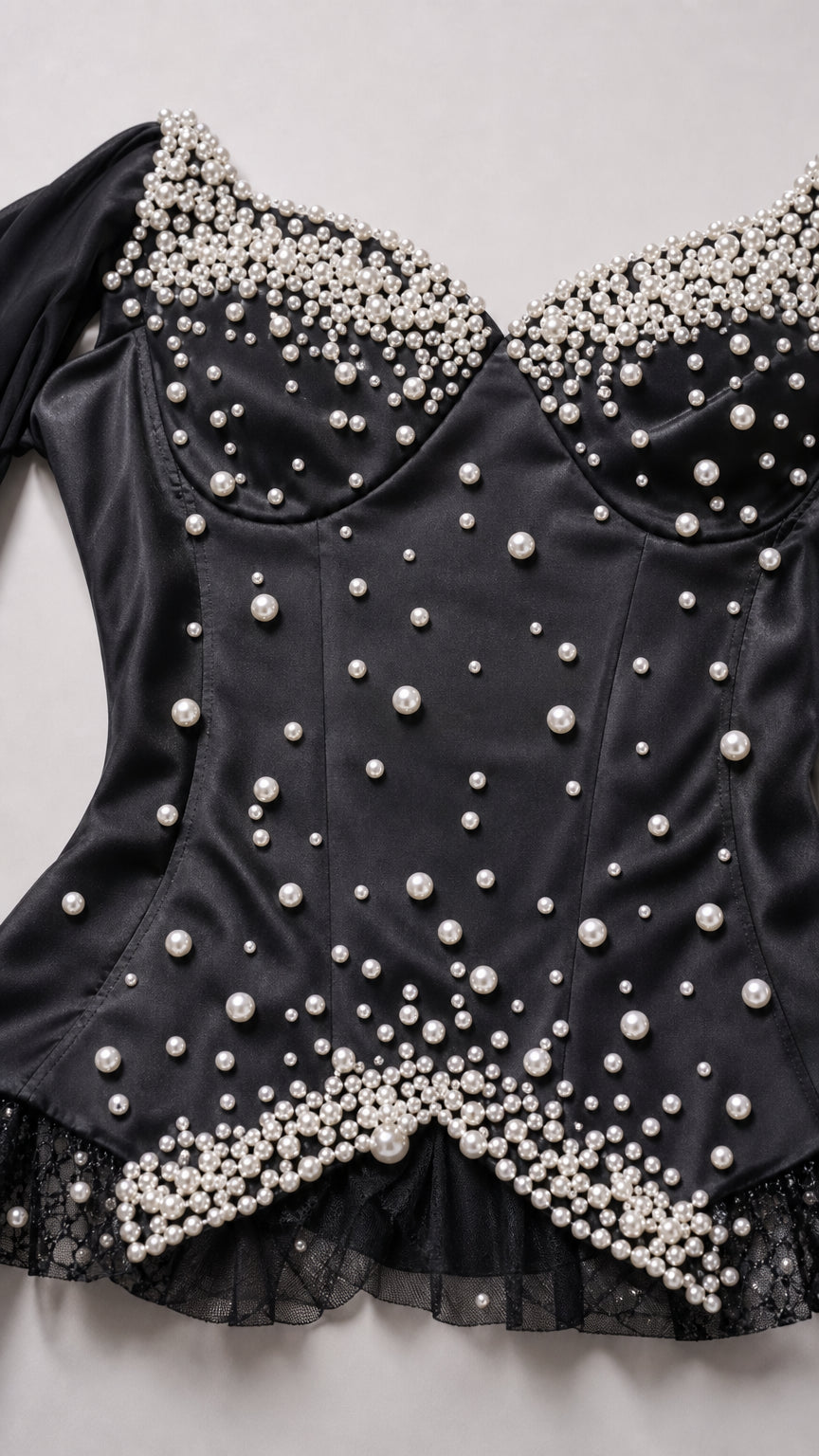 Close-up detail of structured corset bodice embellished with graduated white faux pearls and lace trim
