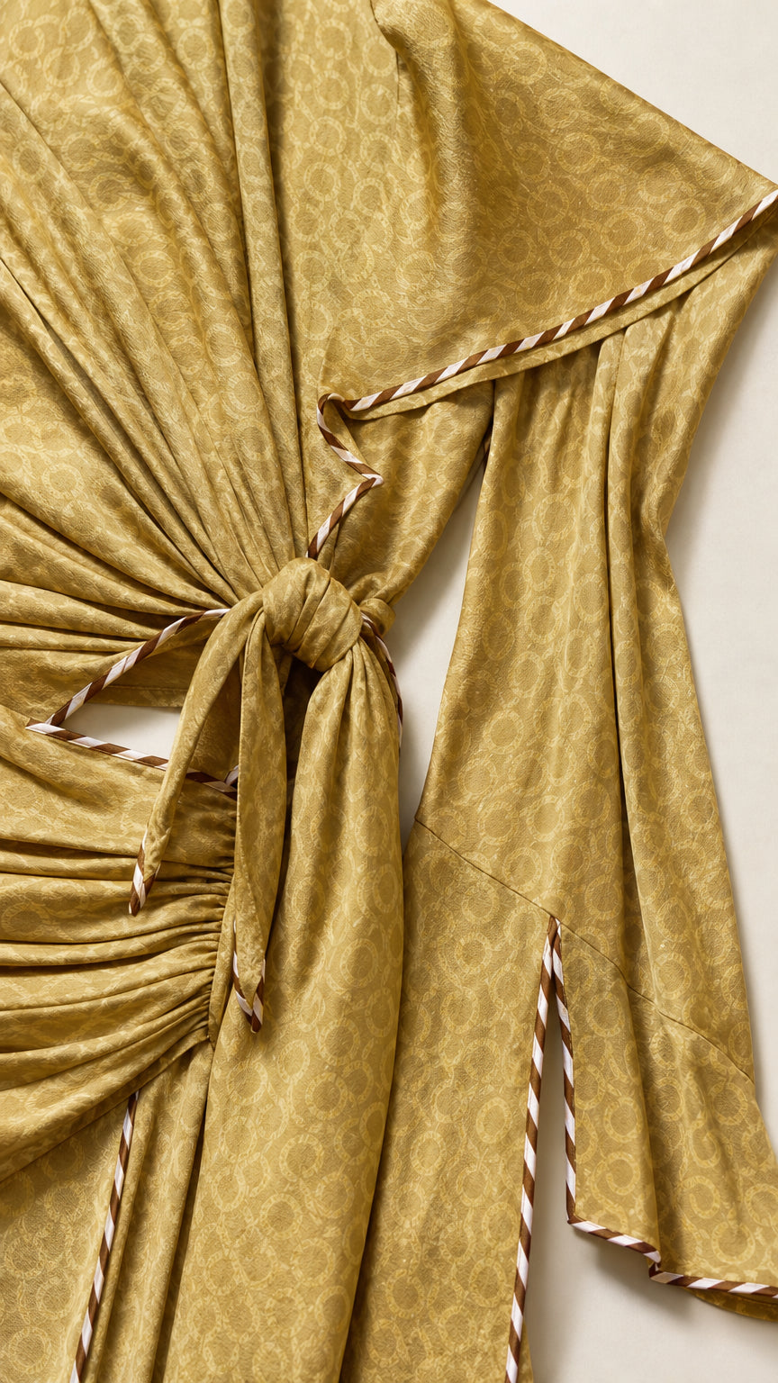 Close-up detail of side knot cutout and contrast striped piping on slit sleeves in Olive Gold