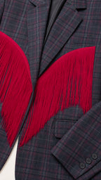 Close-up detail of plaid woven fabric, notched lapel, and red fringe embellishment