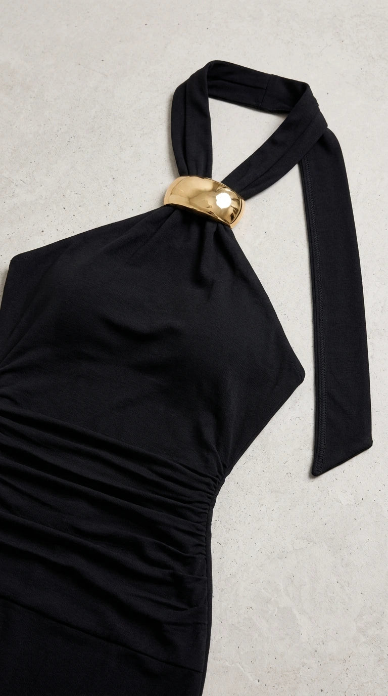 Close up of black halter neckline with polished gold metal accent ring and gathered fabric