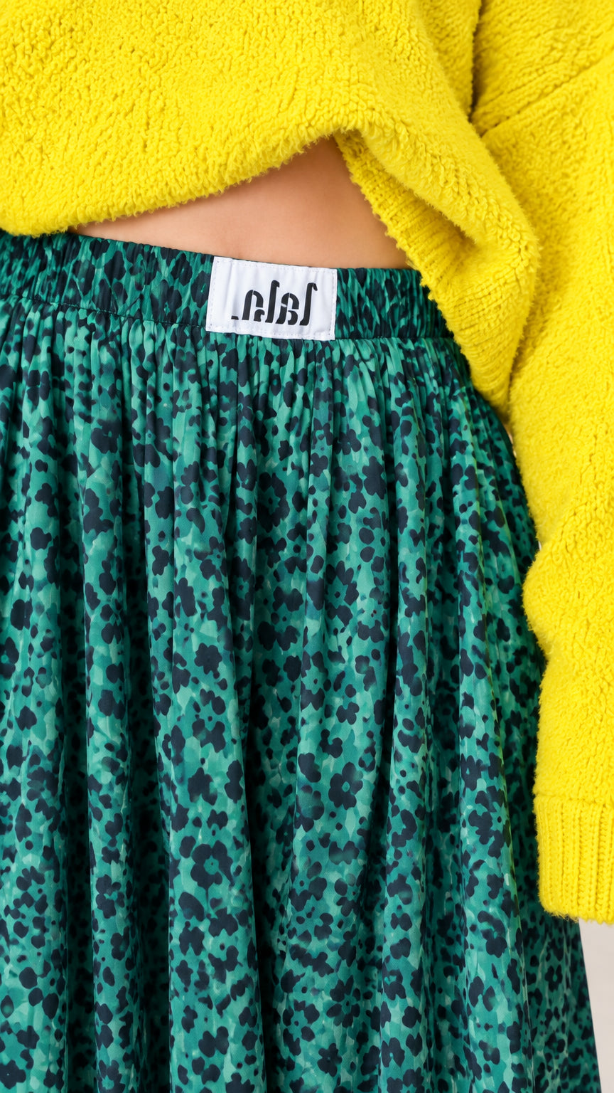 Close-up detail of gathered elastic waistband and emerald green leopard print fabric texture