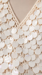 Close-up detail of white crochet knit and round disc paillette embellishments