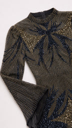 Close-up detail of intricate beadwork, high collar, and flared sleeve on formal evening dress