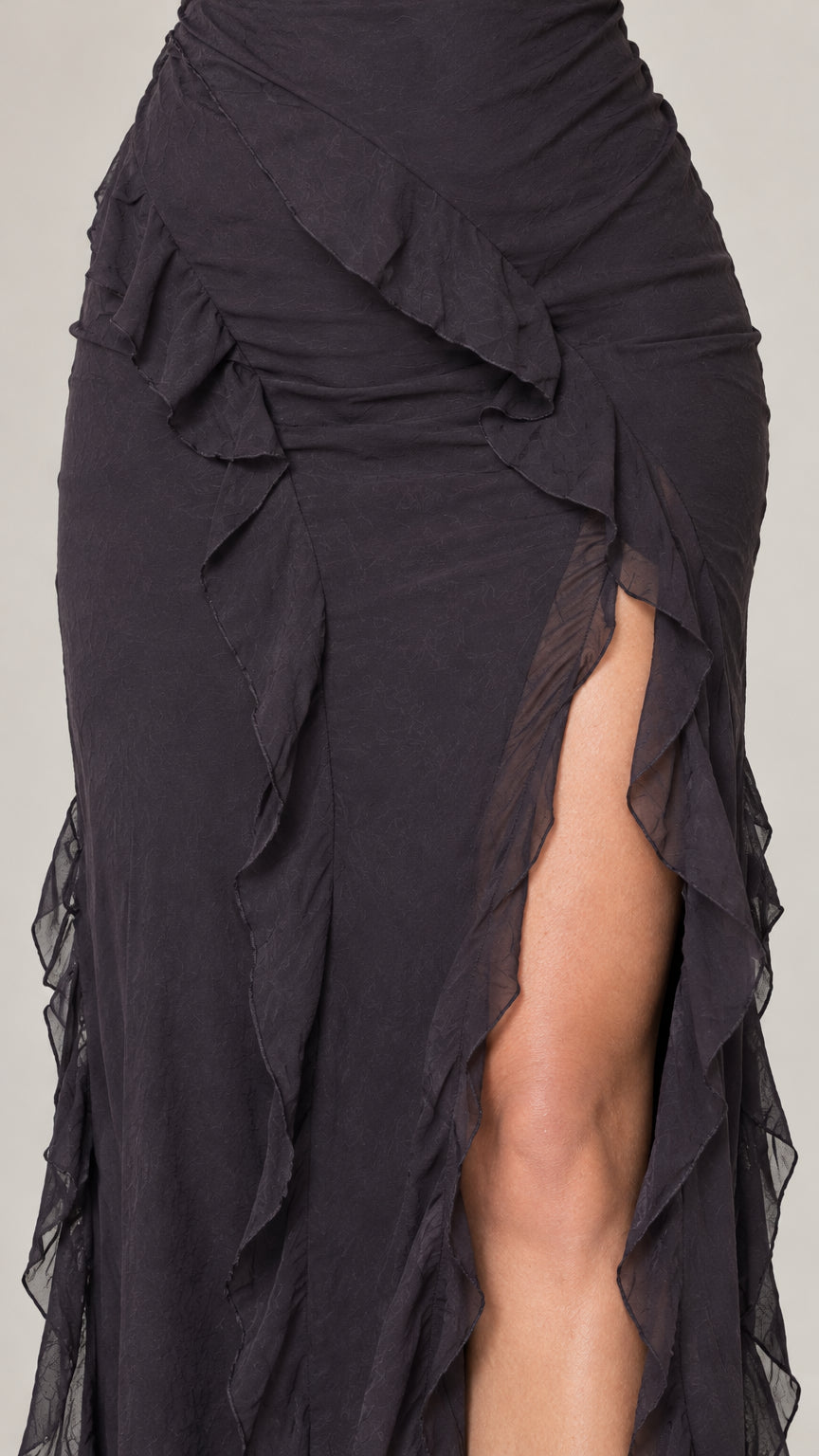 Close-up detail of cascade ruffle trim and side thigh slit on black dress