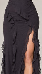 Close-up detail of cascade ruffle trim and side thigh slit on black dress
