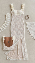 Flat lay view of white floral lace gown detailing ruffled straps, gathered bodice, and side slit