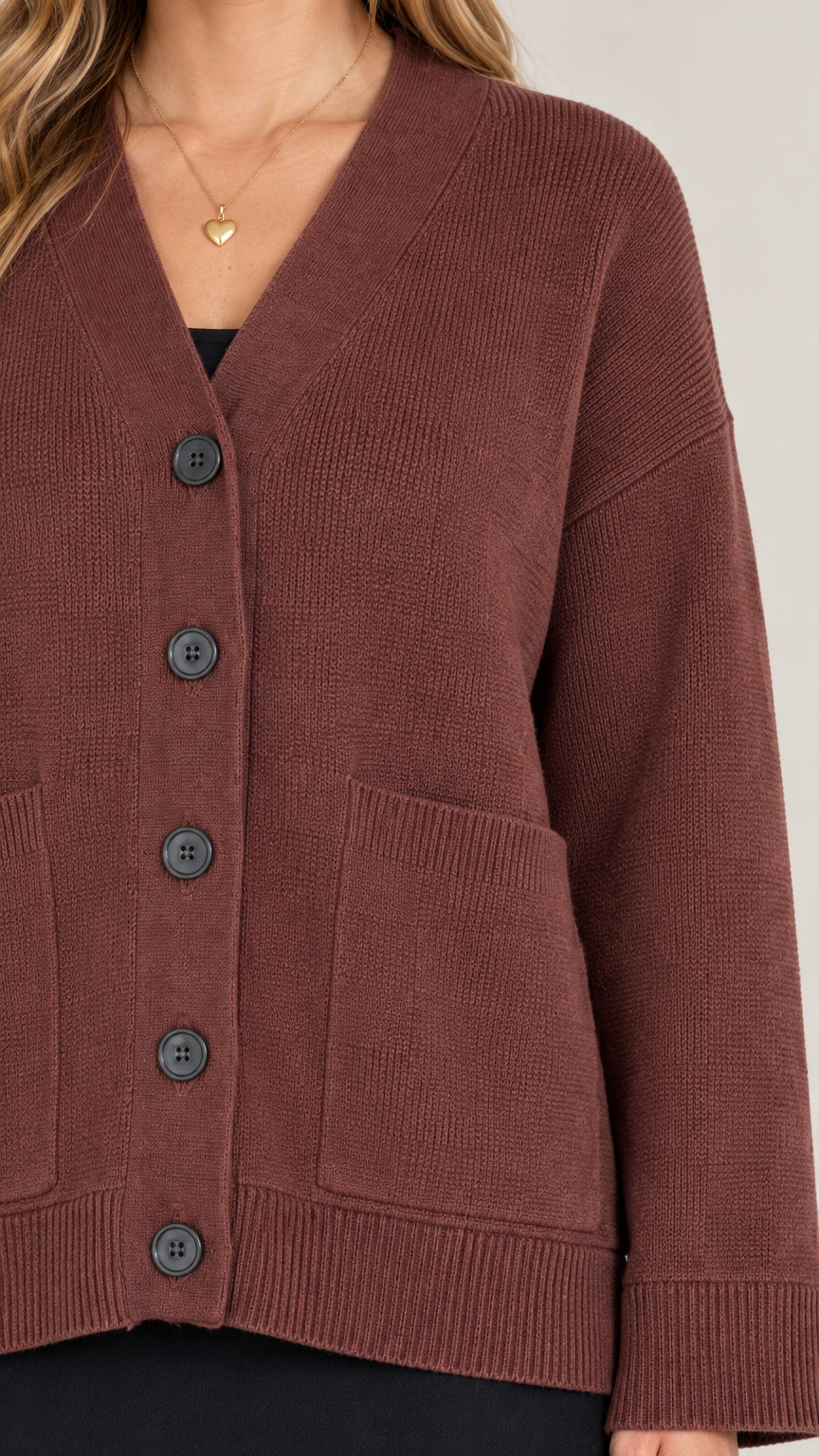 Close-up detail of brown knit cardigan showing five-button placket, patch pocket, and rib knit hem
