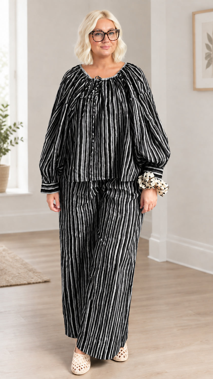 Full front view of model wearing black and white striped two-piece pant set