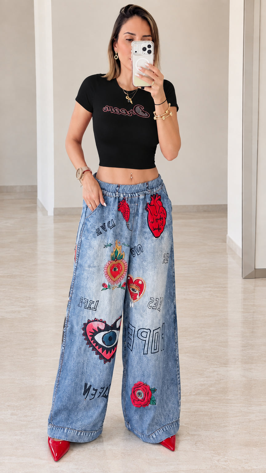 Front view of woman wearing black cropped tee with blue wide-leg graphic pants