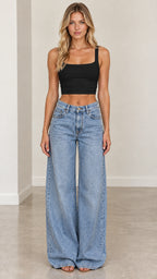 Full-body front view of woman wearing light blue wide-leg jeans styled with black crop top