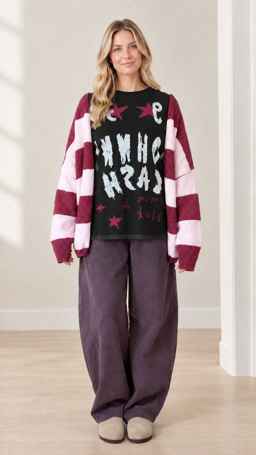 Full front view of model wearing black graphic top with striped cardigan and wide leg pants