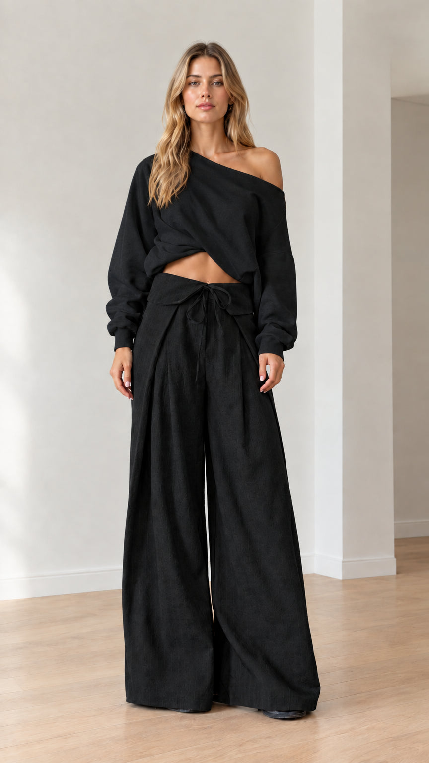 Model wearing full black off-the-shoulder top and fold-over wide-leg pants set