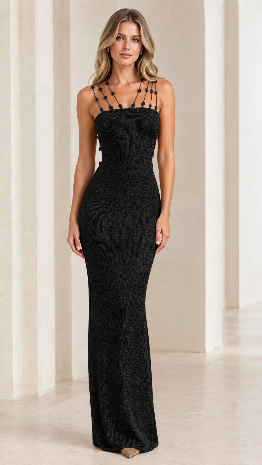 Model wearing black metallic knit sleeveless maxi dress with charm-embellished straps