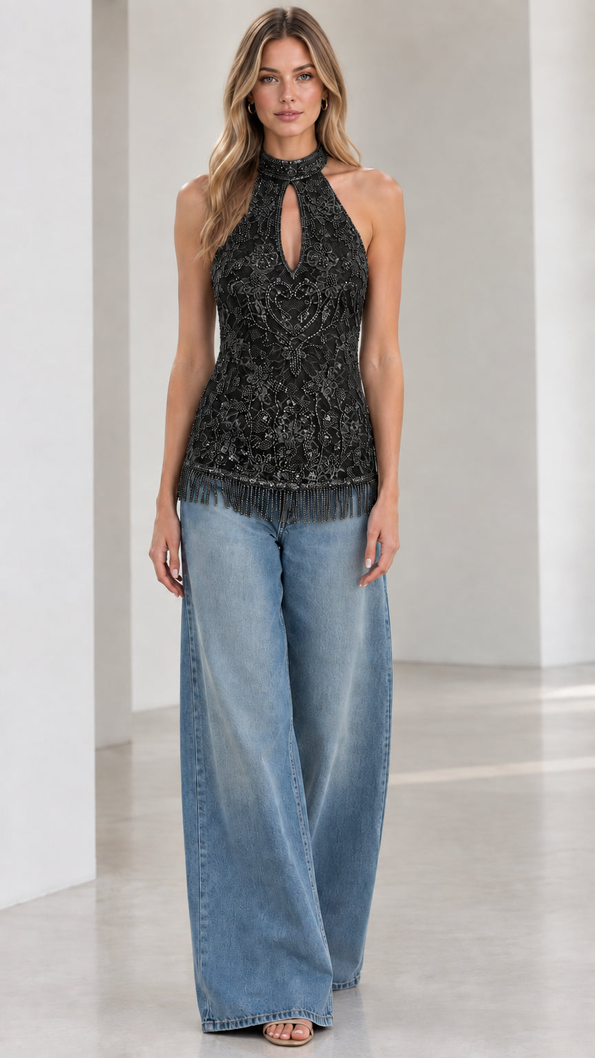 Black embellished halter top with beaded fringe hem worn by model with wide-leg jeans