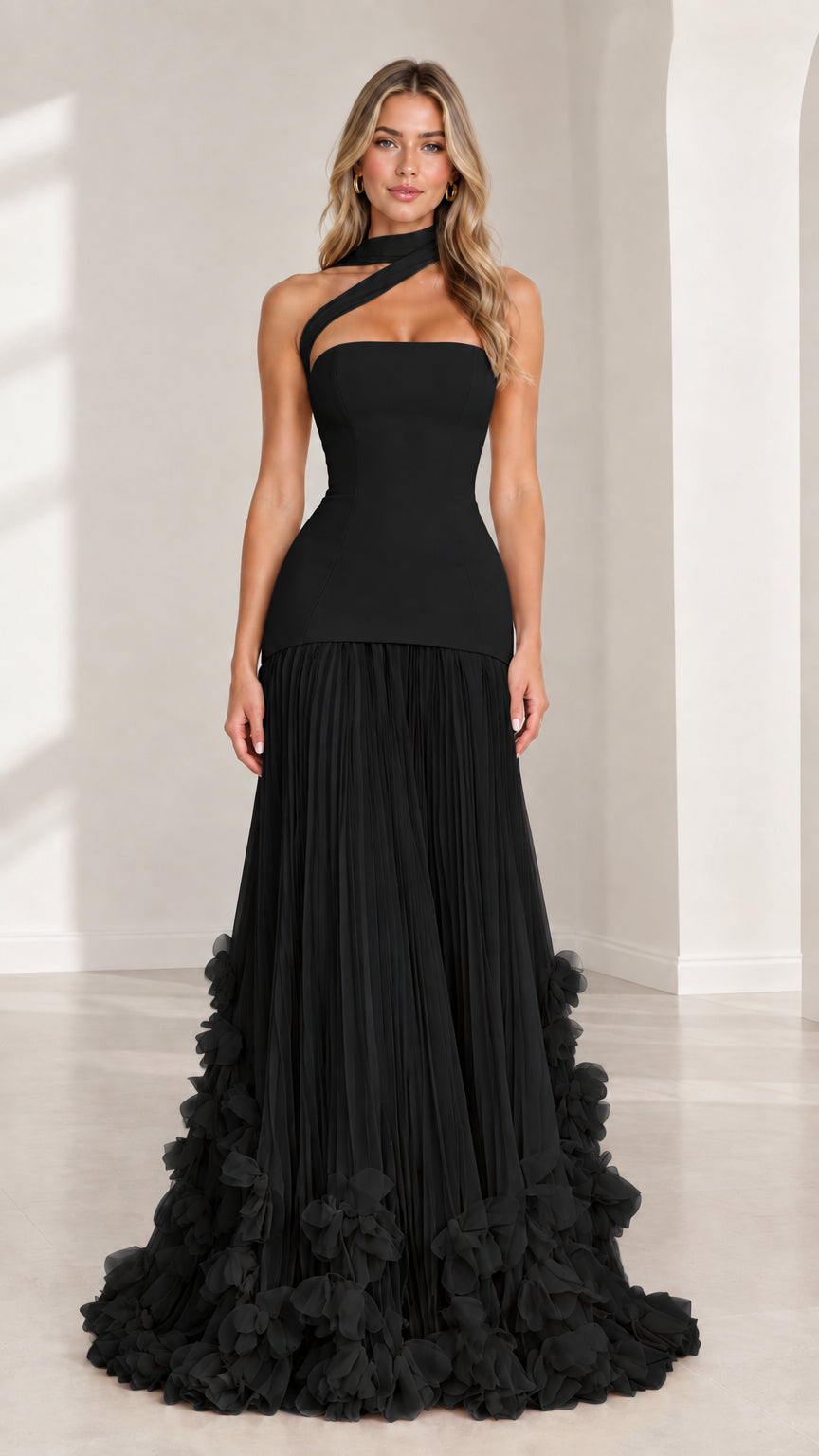 Front full-length view of model wearing black asymmetric drop waist pleated evening gown