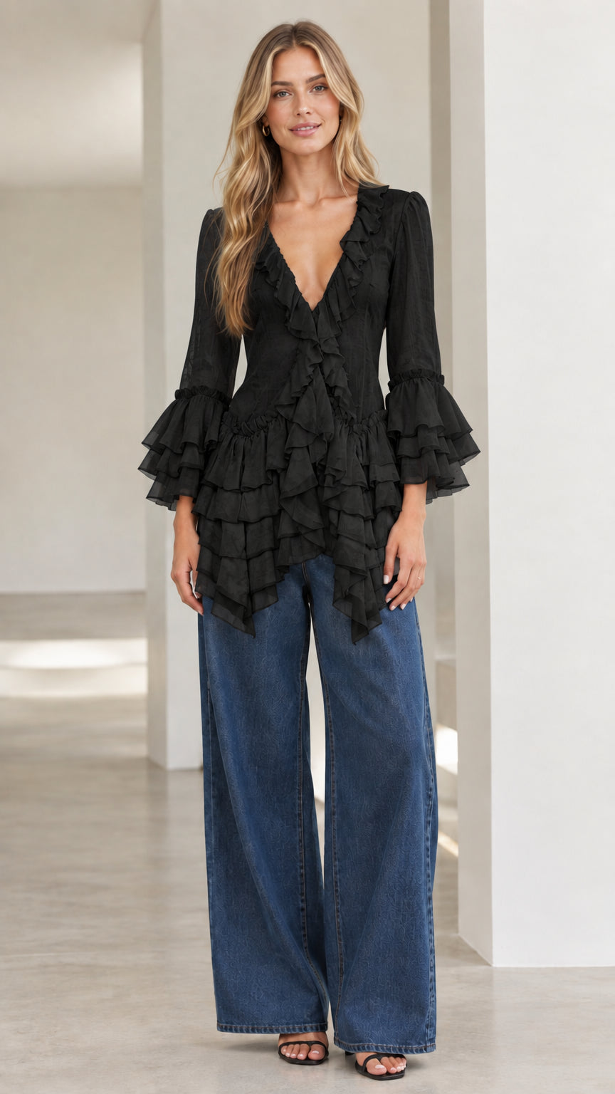 Model wearing black tiered ruffle V-neck blouse with wide-leg denim